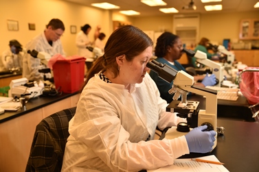 Woman student at a microscope learning Medical Lab Technology.