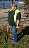 Lyn Nitz holding a shovel outside on the grass. 