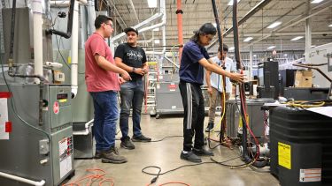 4 students in air conditioning class testing out the machinery