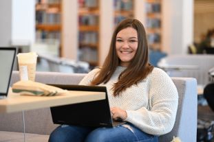 Student sitting down in the library lounging area with her laptop.