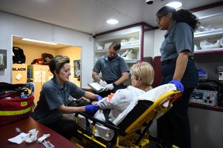 Paramedic students performing a simulation inside a makeshift ambulance. 