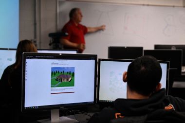 Computer graphic Technology Student sitting down with his design layout displayed on PC. 