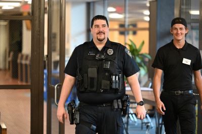 A police officer and a student walking past the college center.