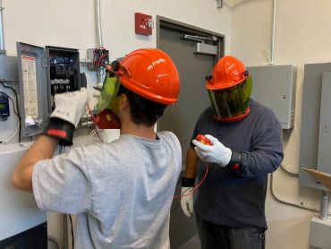 Electrical Engineering Solar Class with two students fixing up a wiring system with hats on. 