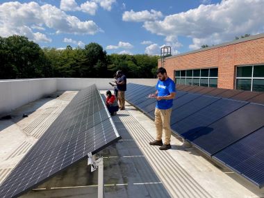 Two students that are experimenting with solar panels on a rooftop