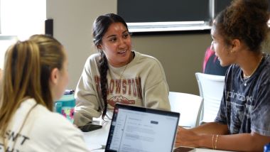 Three students in Professor Kenneth West's classroom having a discussion