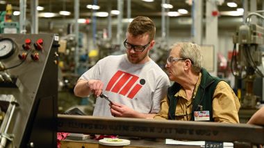 A professor showing a student how a student how to operate tool in machine tool class