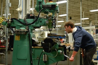 Machine Tool student using a stick to lift a function of the machine upwards. 