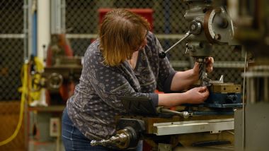 A student operating on machinery in machine tool class