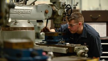 A student operating on machinery in machine tool class